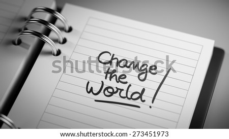 Closeup of a personal agenda setting an important date representing a time schedule. The words Change the world written on a white notebook to remind you an important appointment.