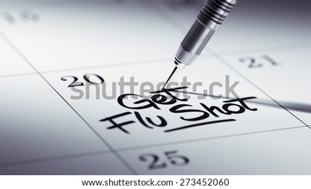 Concept image of a Calendar with a golden dart stick. The words Get Flu Shot written on a white notebook to remind you an important appointment.