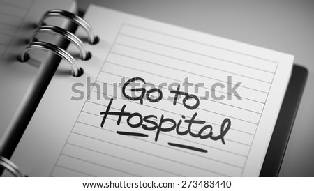 Closeup of a personal agenda setting an important date representing a time schedule. The words Go to Hospital written on a white notebook to remind you an important appointment.