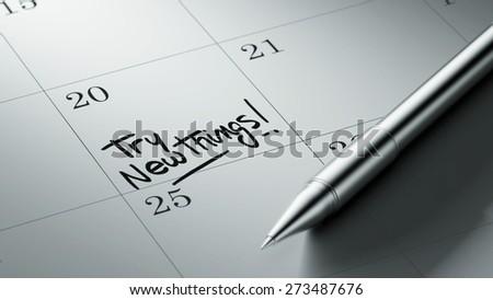 Closeup of a personal agenda setting an important date written with pen. The words Try new things written on a white notebook to remind you an important appointment.