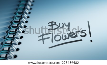 Closeup of a personal calendar setting an important date representing a time schedule. The words Buy Flowers written on a white notebook to remind you an important appointment.