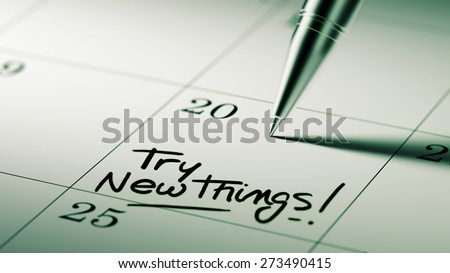 Closeup of a personal agenda setting an important date written with pen. The words Try new things written on a white notebook to remind you an important appointment.