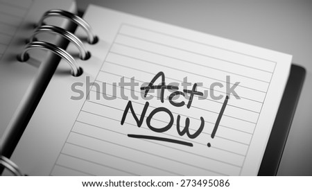 Closeup of a personal agenda setting an important date representing a time schedule. The words Act Now written on a white notebook to remind you an important appointment.