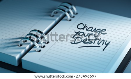 Closeup of a personal agenda setting an important date representing a time schedule. The words Change your destiny written on a white notebook to remind you an important appointment.