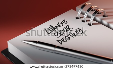 Closeup of a personal agenda setting an important date writing with pen. The words Change your destiny written on a white notebook to remind you an important appointment.