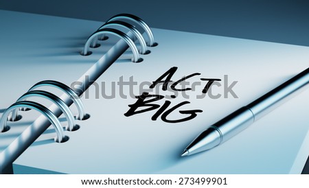 Closeup of a personal agenda setting an important date writing with pen. The words Act BIG written on a white notebook to remind you an important appointment.