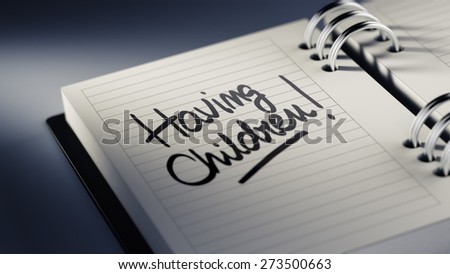 Closeup of a personal agenda setting an important date representing a time schedule. The words Having Children written on a white notebook to remind you an important appointment.