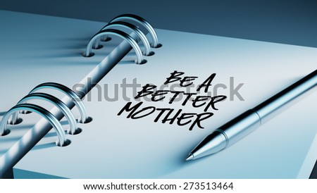 Closeup of a personal agenda setting an important date writing with pen. The words Be a better mother written on a white notebook to remind you an important appointment.