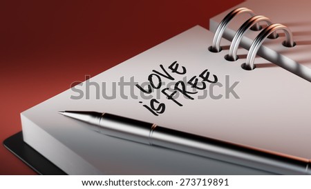 Closeup of a personal agenda setting an important date writing with pen. The words Love is Free written on a white notebook to remind you an important appointment.