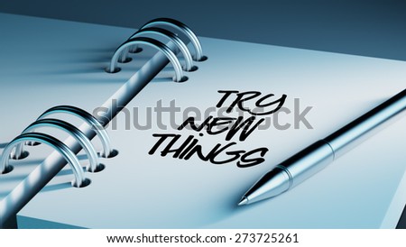 Closeup of a personal agenda setting an important date writing with pen. The words Try new things written on a white notebook to remind you an important appointment.