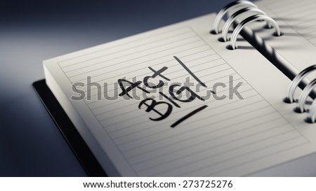 Closeup of a personal agenda setting an important date representing a time schedule. The words Act BIG written on a white notebook to remind you an important appointment.