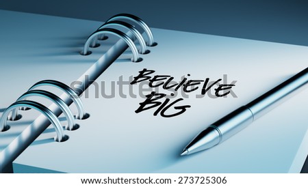 Closeup of a personal agenda setting an important date writing with pen. The words Believe BIG written on a white notebook to remind you an important appointment.