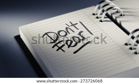 Closeup of a personal agenda setting an important date representing a time schedule. The words Don\'t Fear written on a white notebook to remind you an important appointment.