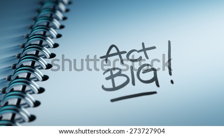 Closeup of a personal calendar setting an important date representing a time schedule. The words Act BIG written on a white notebook to remind you an important appointment.