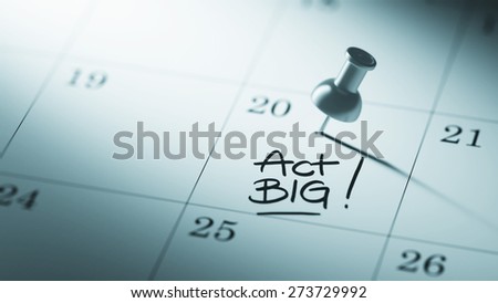 Concept image of a Calendar with a push pin. Closeup shot of a thumbtack attached. The words Act BIG written on a white notebook to remind you an important appointment.