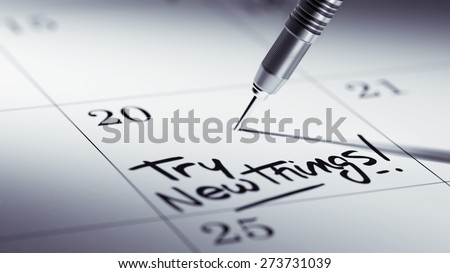Concept image of a Calendar with a golden dart stick. The words Try new things written on a white notebook to remind you an important appointment.