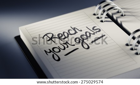 Closeup of a personal agenda setting an important date representing a time schedule. The words Reach your goals written on a white notebook to remind you an important appointment.
