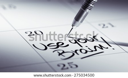 Concept image of a Calendar with a golden dart stick. The words Use your Brain written on a white notebook to remind you an important appointment.