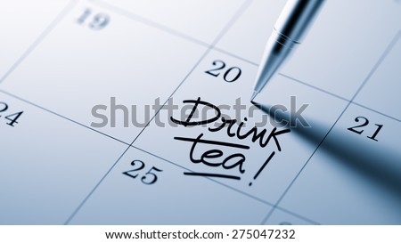Closeup of a personal agenda setting an important date written with pen. The words Drink Tea written on a white notebook to remind you an important appointment.