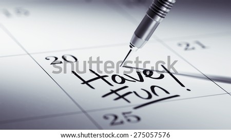 Concept image of a Calendar with a golden dart stick. The words Have Fun written on a white notebook to remind you an important appointment.