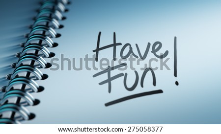 Closeup of a personal calendar setting an important date representing a time schedule. The words Have Fun written on a white notebook to remind you an important appointment.