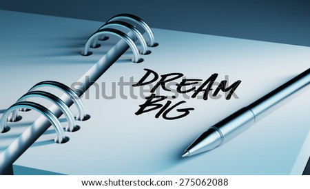Closeup of a personal agenda setting an important date writing with pen. The words Dream big written on a white notebook to remind you an important appointment.