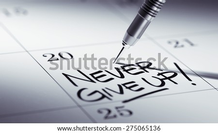 Concept image of a Calendar with a golden dart stick. The words Never give up written on a white notebook to remind you an important appointment.