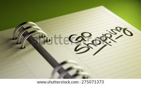 Closeup of a personal agenda setting an important date representing a time schedule. The words Go shopping written on a white notebook to remind you an important appointment.