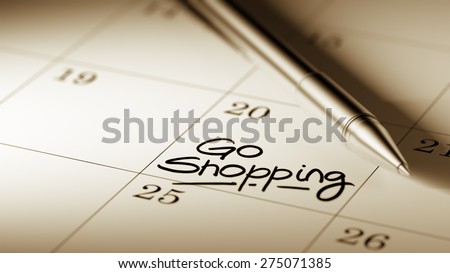 Closeup of a personal agenda setting an important date written with pen. The words Go shopping written on a white notebook to remind you an important appointment.