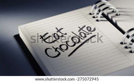 Closeup of a personal agenda setting an important date representing a time schedule. The words Eat Chocolate written on a white notebook to remind you an important appointment.