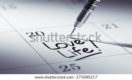 Concept image of a Calendar with a golden dart stick. The words Love life written on a white notebook to remind you an important appointment.