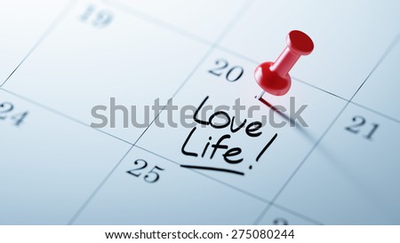 Concept image of a Calendar with a red push pin. Closeup shot of a thumbtack attached. The words Love life written on a white notebook to remind you an important appointment.
