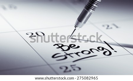 Concept image of a Calendar with a golden dart stick. The words Be Strong written on a white notebook to remind you an important appointment.