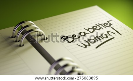 Closeup of a personal agenda setting an important date representing a time schedule. The words Be a better woman written on a white notebook to remind you an important appointment.