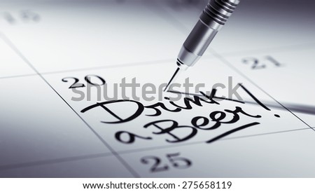 Concept image of a Calendar with a golden dart stick. The words Drink a beer written on a white notebook to remind you an important appointment.