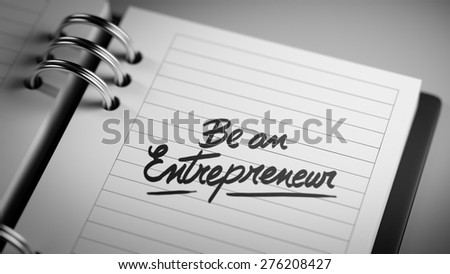 Closeup of a personal agenda setting an important date representing a time schedule. The words Be an entrepreneur written on a white notebook to remind you an important appointment.