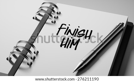 Closeup of a personal agenda setting an important date writing with pen. The words Finish Him written on a white notebook to remind you an important appointment.