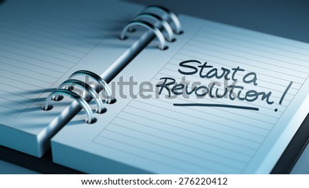 Closeup of a personal agenda setting an important date representing a time schedule. The words Start Revolution written on a white notebook to remind you an important appointment.