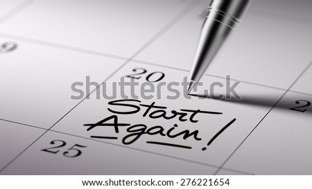 Closeup of a personal agenda setting an important date written with pen. The words Start Again written on a white notebook to remind you an important appointment.