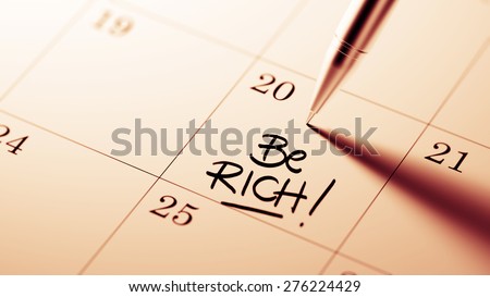 Closeup of a personal agenda setting an important date written with pen. The words Be Rich written on a white notebook to remind you an important appointment.