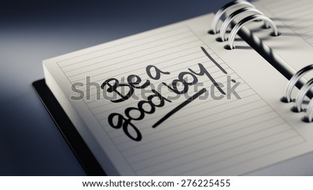 Closeup of a personal agenda setting an important date representing a time schedule. The words Be a good boy written on a white notebook to remind you an important appointment.