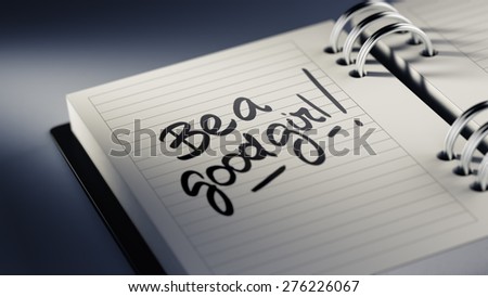 Closeup of a personal agenda setting an important date representing a time schedule. The words Be a good girl written on a white notebook to remind you an important appointment.