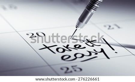 Concept image of a Calendar with a golden dart stick. The words Take it easy written on a white notebook to remind you an important appointment.
