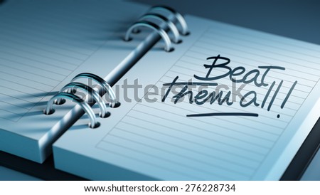 Closeup of a personal agenda setting an important date representing a time schedule. The words Beat them all written on a white notebook to remind you an important appointment.