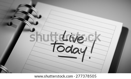 Closeup of a personal agenda setting an important date representing a time schedule. The words Live today written on a white notebook to remind you an important appointment.