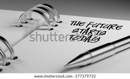 Closeup of a personal agenda setting an important date writing with pen. The words The future starts today written on a white notebook to remind you an important appointment.
