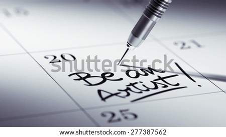 Concept image of a Calendar with a golden dart stick. The words Be an Artist written on a white notebook to remind you an important appointment.