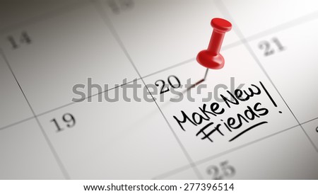 Concept image of a Calendar with a red push pin. Closeup shot of a thumbtack attached. The words Make new friends written on a white notebook to remind you an important appointment.