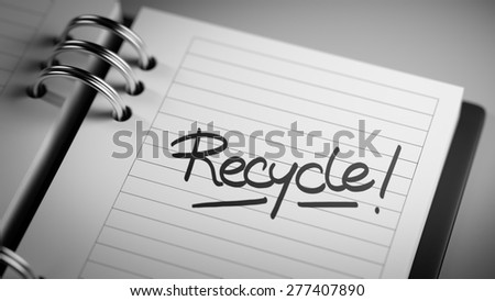 Closeup of a personal agenda setting an important date representing a time schedule. The words Recycle written on a white notebook to remind you an important appointment.