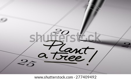 Closeup of a personal agenda setting an important date written with pen. The words Plant a tree written on a white notebook to remind you an important appointment.